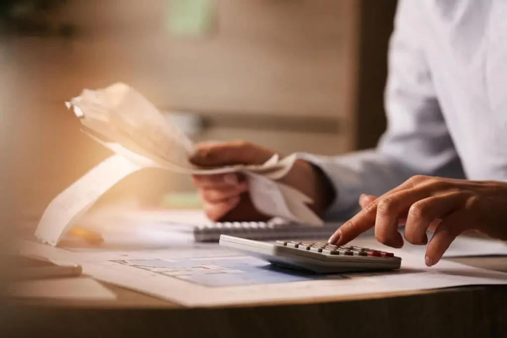 Disciplina financeira: economista usando calculadora ao passar por contas e impostos no escritório